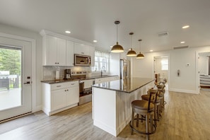 A modern kitchen with white cabinetry, stainless steel appliances, and a central island with bar stools. - Hot Tub & Fenced Yard! Family Escape in Lancaster (Lancaster)