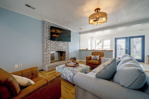 A living room with a brick fireplace, a sofa, a chair, and a television. - Salty Chateau Home w/ Ocean Views, Surf City (Surf City)