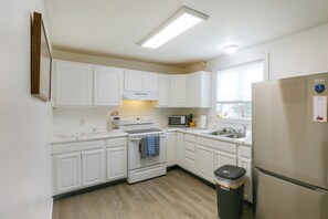 A compact kitchen with white cabinetry, a stove, a microwave, and a refrigerator. - Northern Lights Getaway: Fairbanks Home (Fairbanks)