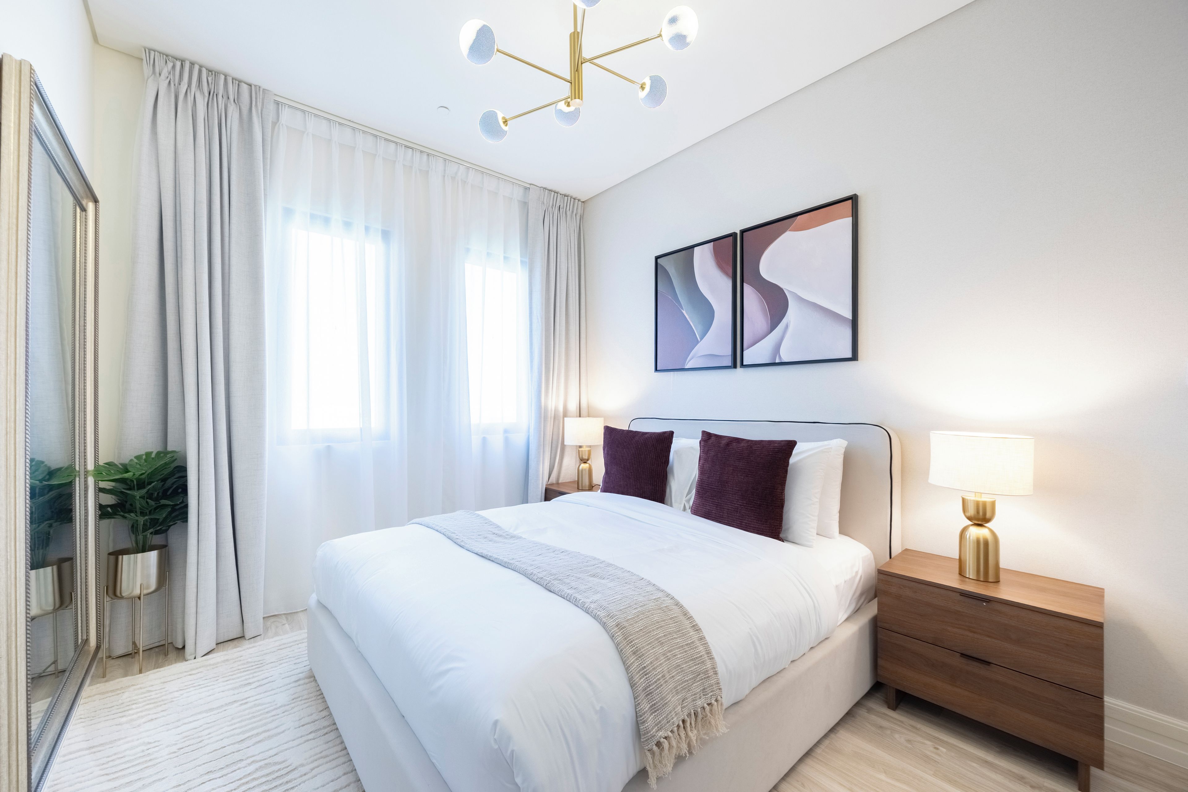 Ein modernes Hotelzimmer mit einem großen Bett, Nachttischen, einem Spiegel und einer Deckenleuchte.