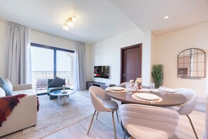 A modern living room with a dining area, large windows, and a flat-screen TV.