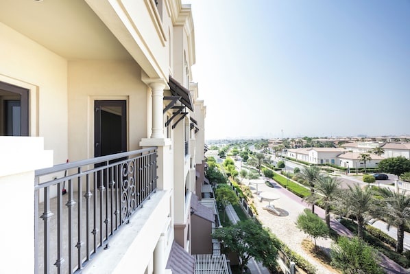 Un balcón con vistas a una zona residencial, que incluye una calle y zonas verdes.