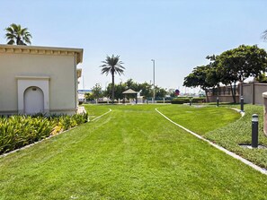 Un área verde bien cuidada con un sendero curvo que conduce a un edificio con entrada arqueada.