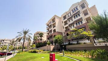 A multi-story residential building with balconies, a well-maintained lawn, and a gated entrance.