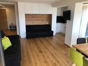 Ein stilvolles Wohnzimmer mit Sofa, Esstisch und Küchenzeile.