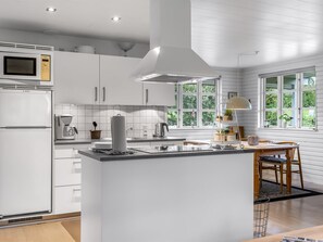 A modern kitchen with white cabinetry, a Bosch microwave, and a large island with a kettle. - "Bennek" - 500m from the sea by Interhome (Egernsund)