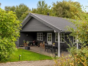 A log cabin with a sloped roof, a covered patio with outdoor furniture, and a fenced garden area. - "Bennek" - 500m from the sea by Interhome (Egernsund)