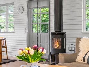 A cozy room with a fireplace, a clock, and a window with greenery outside. - "Bennek" - 500m from the sea by Interhome (Egernsund)