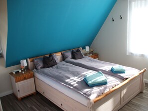 A bedroom with a bed, two bedside tables, a nightstand, and a window with curtains. - Holiday Home in Glowe With Sauna (Glowe)