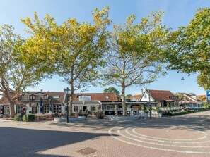 A town square with a cobblestone pavement, trees, and traditional buildings with red-tiled roofs. - Holiday Home With 2 Bedrooms (Burgh-Haamstede)