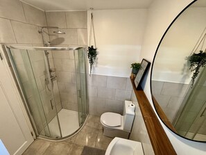 Ein modernes Badezimmer mit Duschkabine aus Glas, Toilette und Waschbecken.