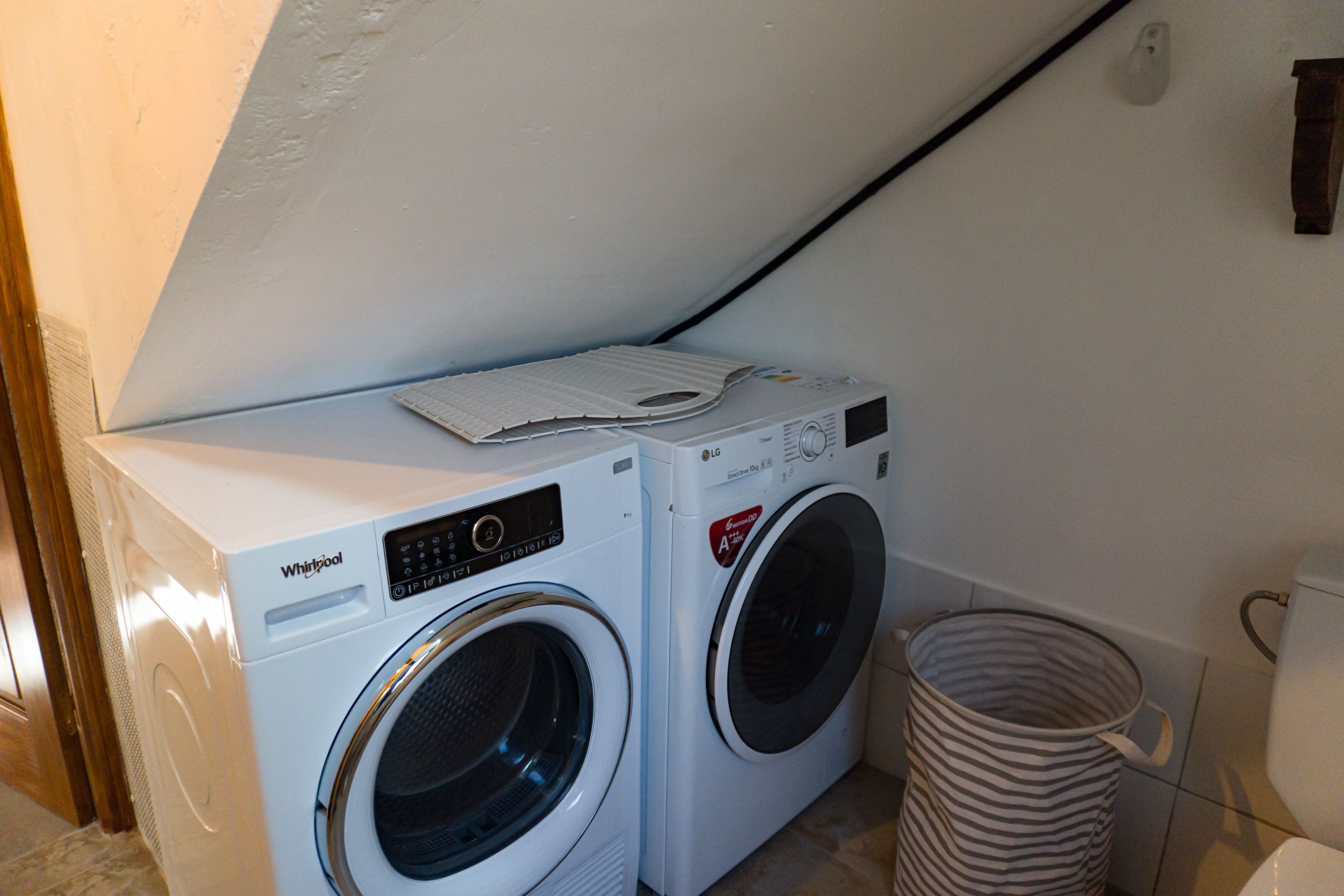 Une buanderie équipée de deux lave-linge Whirlpool blancs et d’un panier à linge empilable.