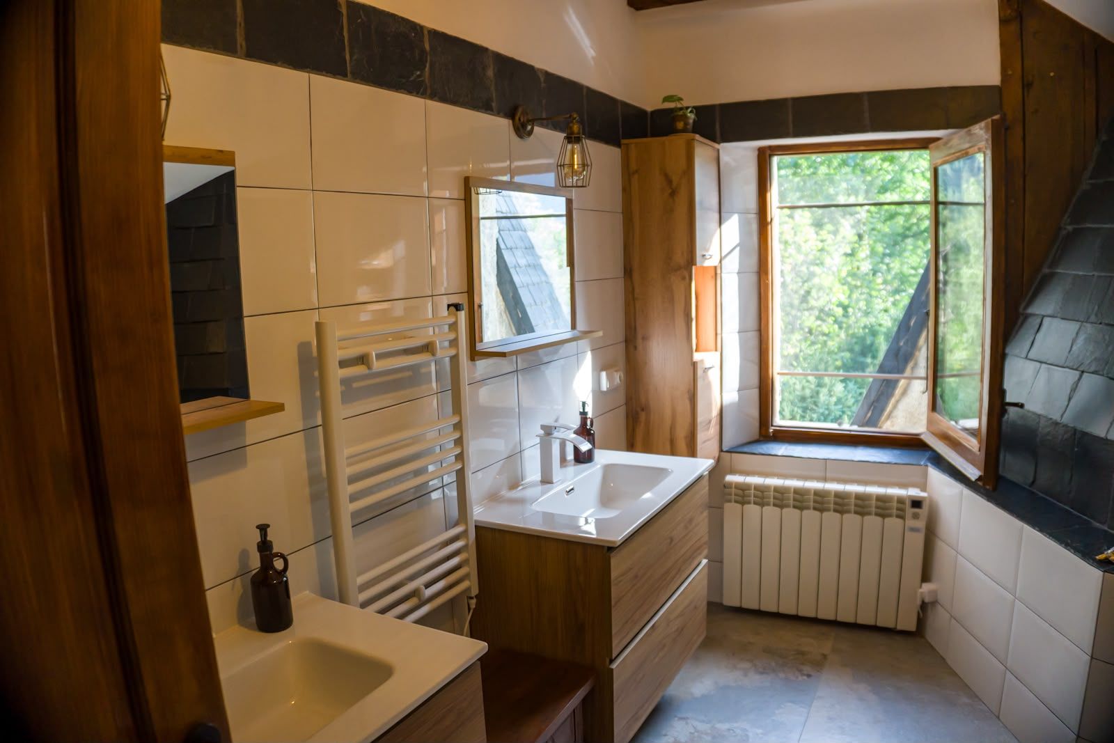 Et badeværelse med et vindue, en radiator, et håndklædetørrestativ og en vask.