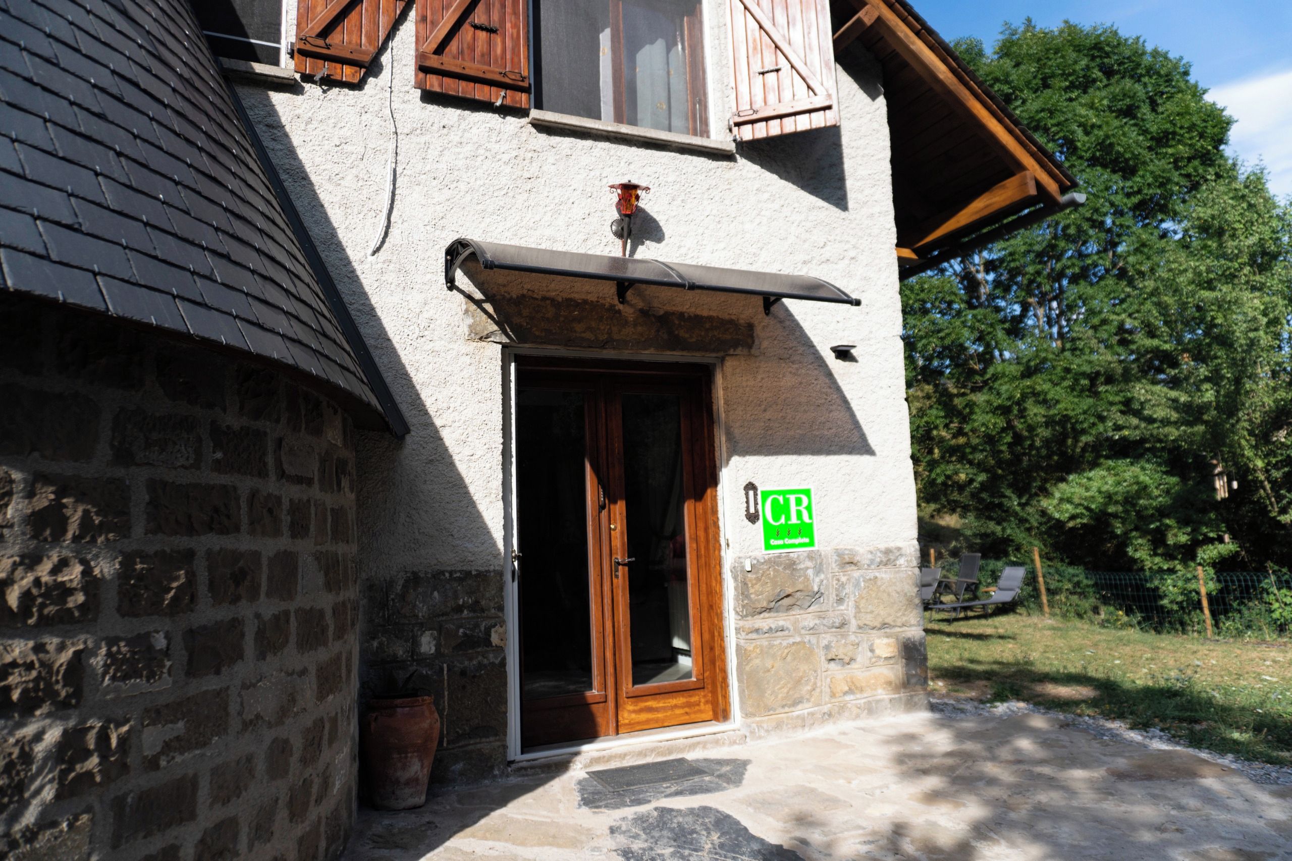 A stone building with a wooden door, a window, and a green sign with 'CR' on it.