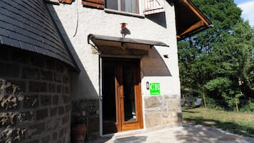 A stone building with a wooden door, a window, and a green sign with 'CR' on it.