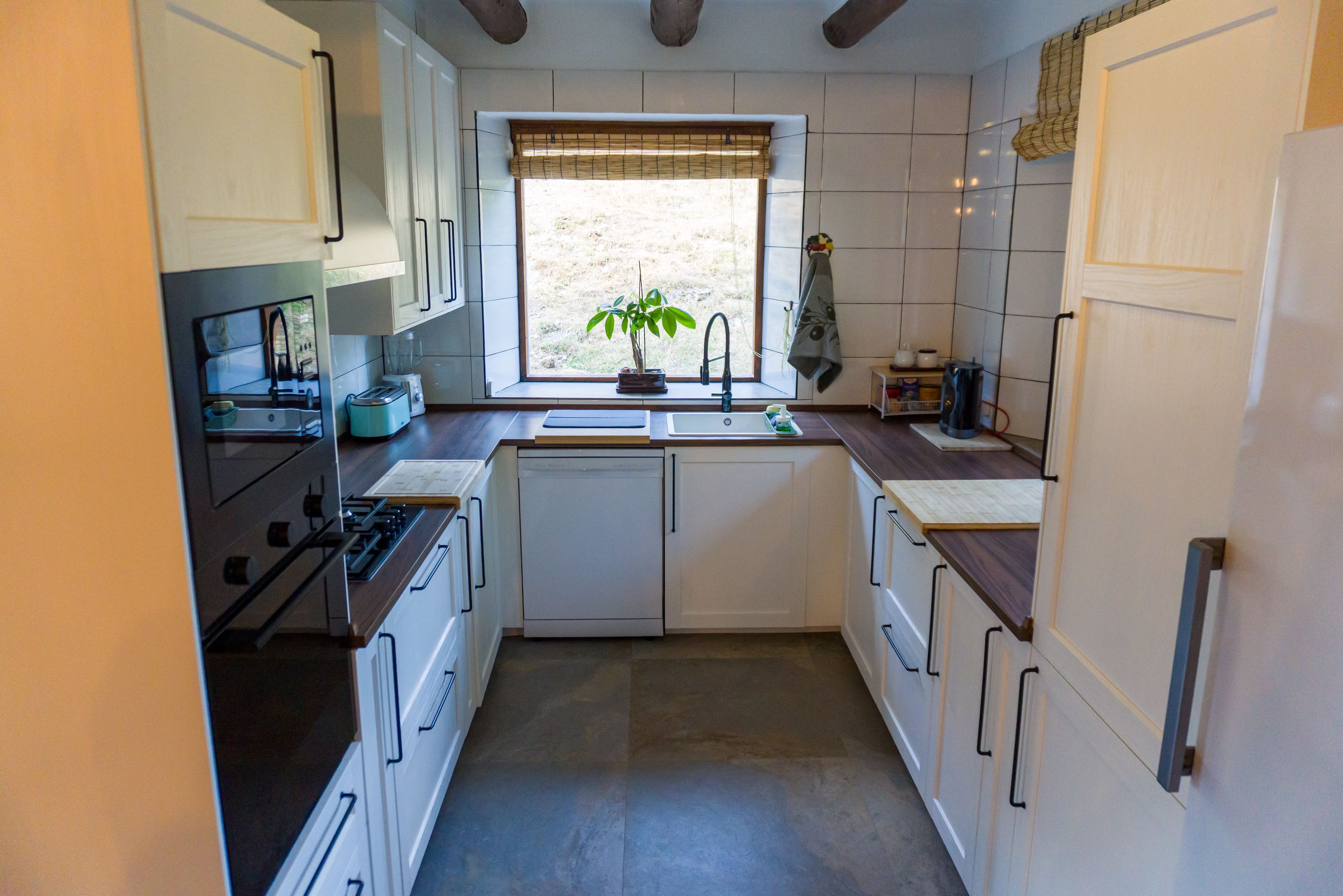 A compact kitchen with a window, a sink, a stove, and cabinets.
