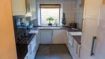 A compact kitchen with a window, a sink, a stove, and cabinets.