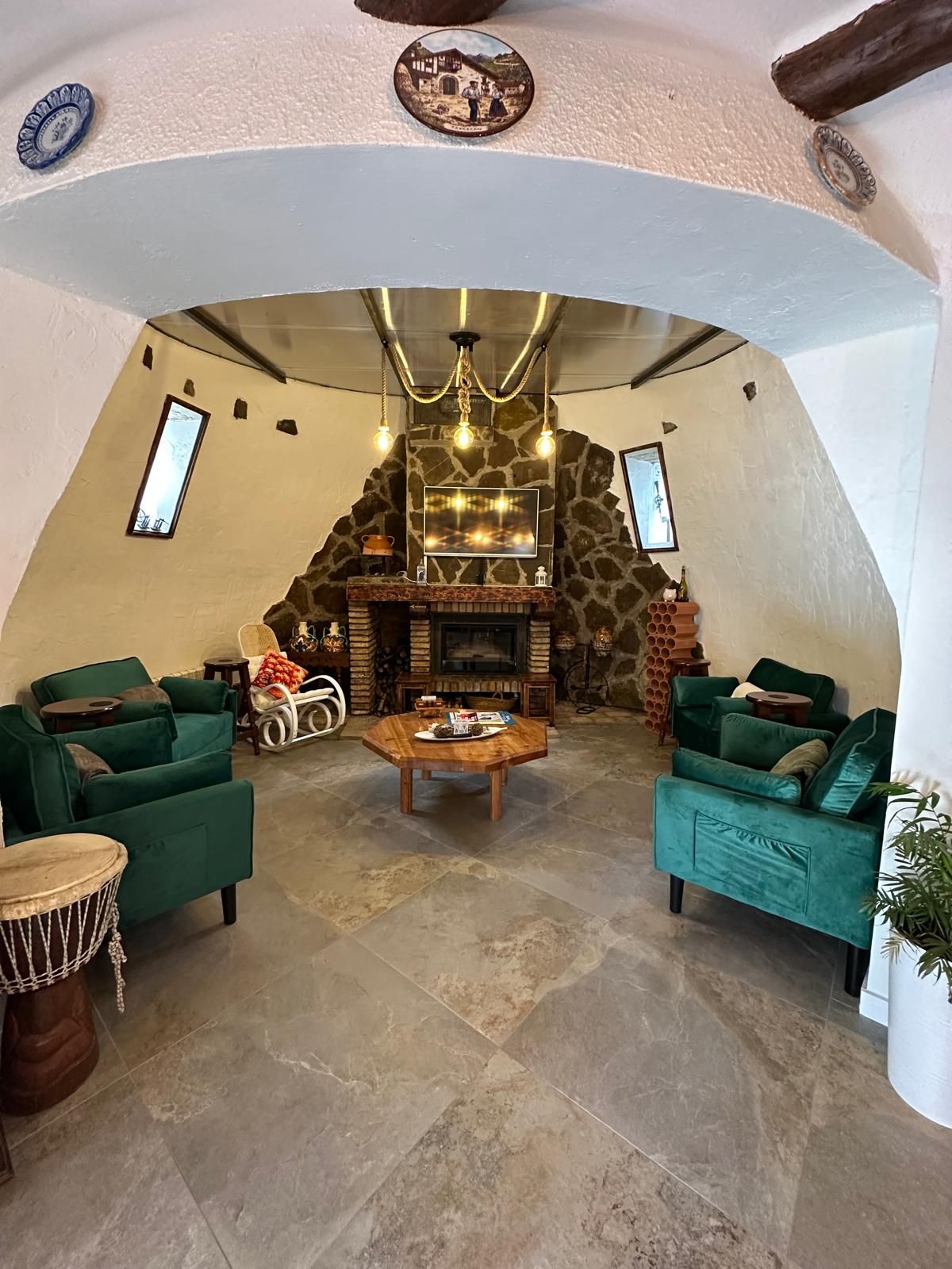 Una sala de estar acogedora con chimenea de piedra, sofás verdes y una mesa de centro.