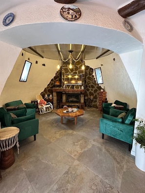 A cozy living room with a stone fireplace, green sofas, and a coffee table.
