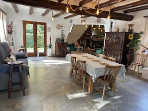 A rustic dining area with a long wooden table, chairs, and a fireplace.