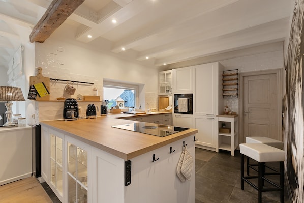 A modern kitchen with an island, built-in appliances, and a view to the outside.