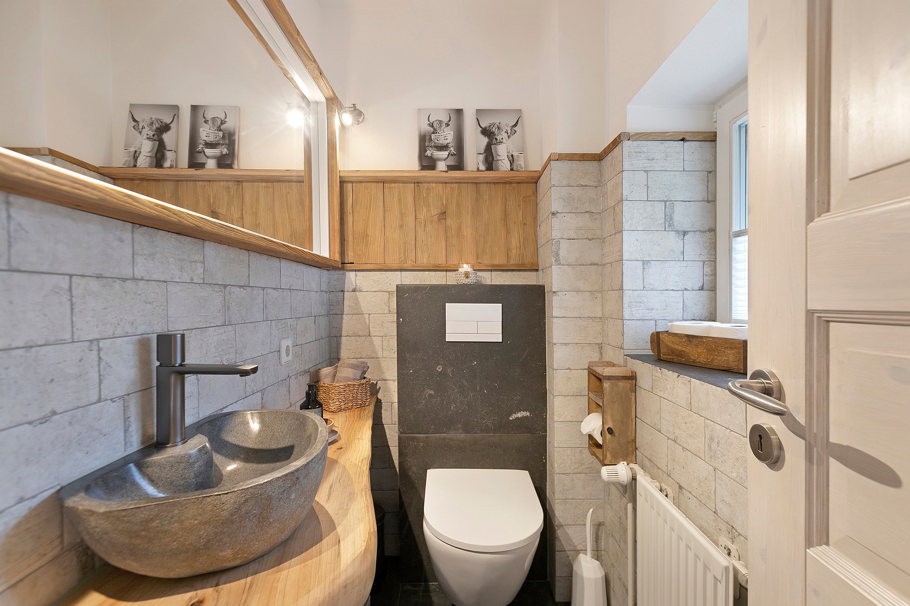 Ein Badezimmer mit einem Steinsink, einer Toilette und einem Spiegel über dem Waschbecken.