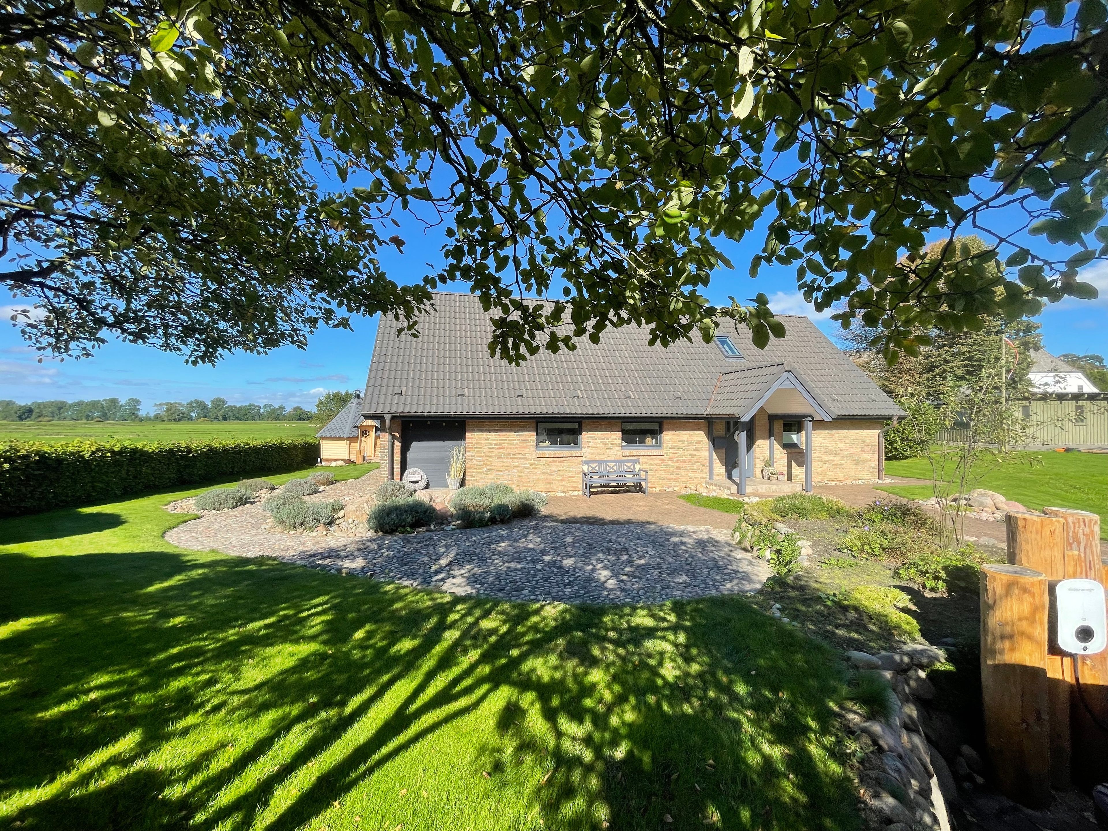 Een huis met een schuin dak, een veranda en een verzorgd gazon.