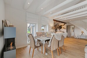 A dining area with a high ceiling, wooden beams, and a view of the outdoors.