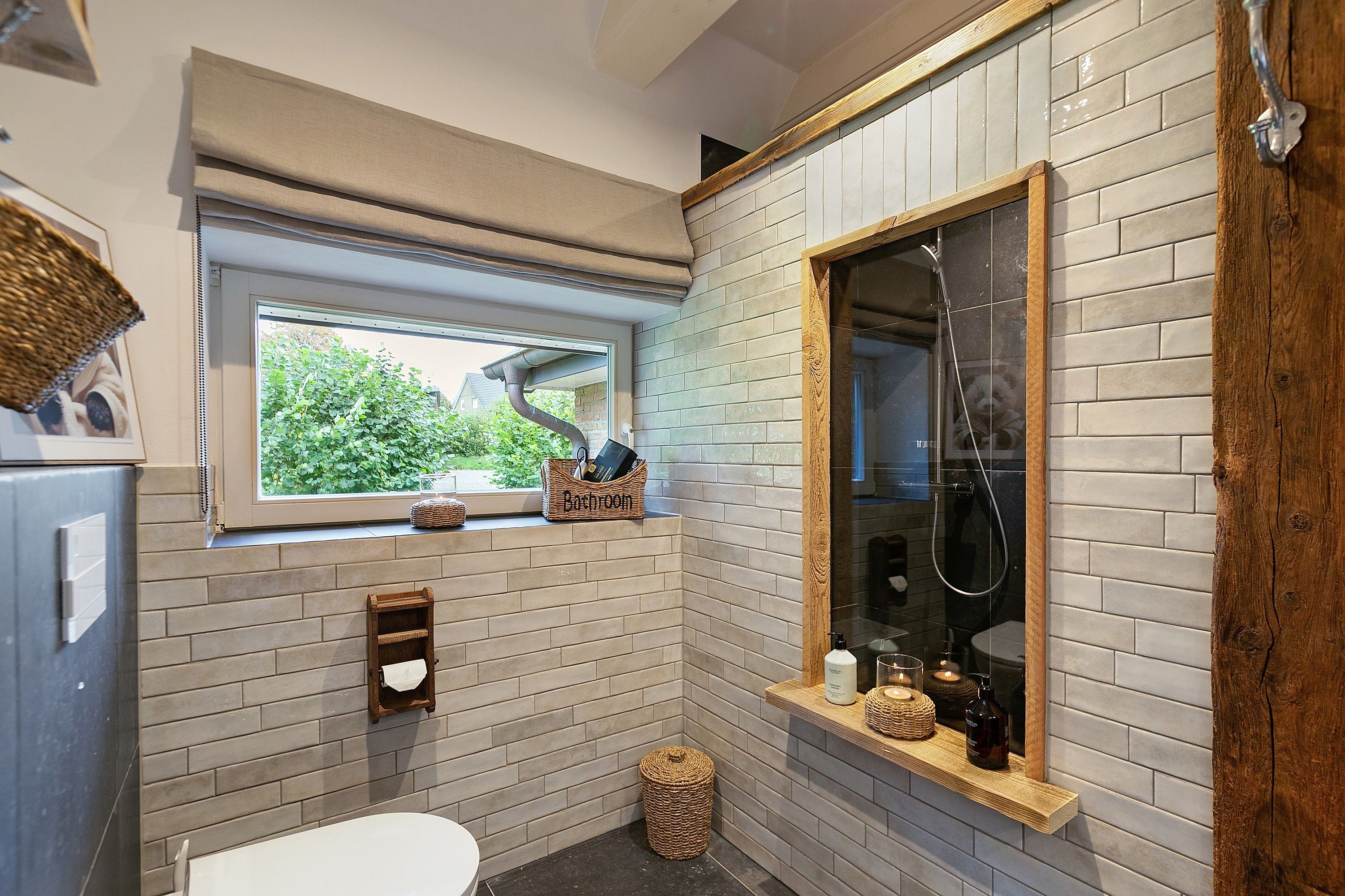A bathroom with a window, a shower, a toilet, and a sink.
