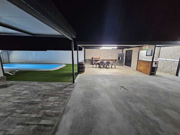 Ein überdachter Außenbereich mit Pool, Sitzgelegenheiten und einer Bar.