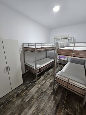 Ein Schlafraum mit Etagenbetten, einem Kleiderschrank und einem Schreibtisch.