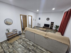 Ein Wohnzimmer mit einer Couch, einem Fernseher und einem Couchtisch.