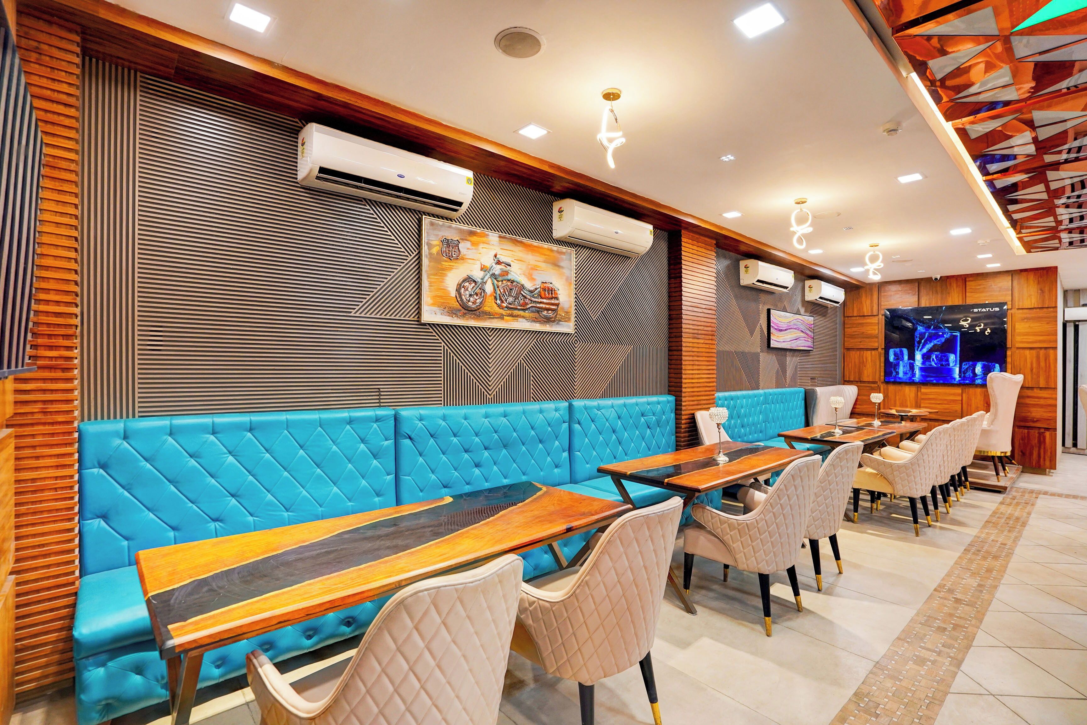 A restaurant interior with blue cushioned seating, wooden tables, and air conditioning units on the walls.