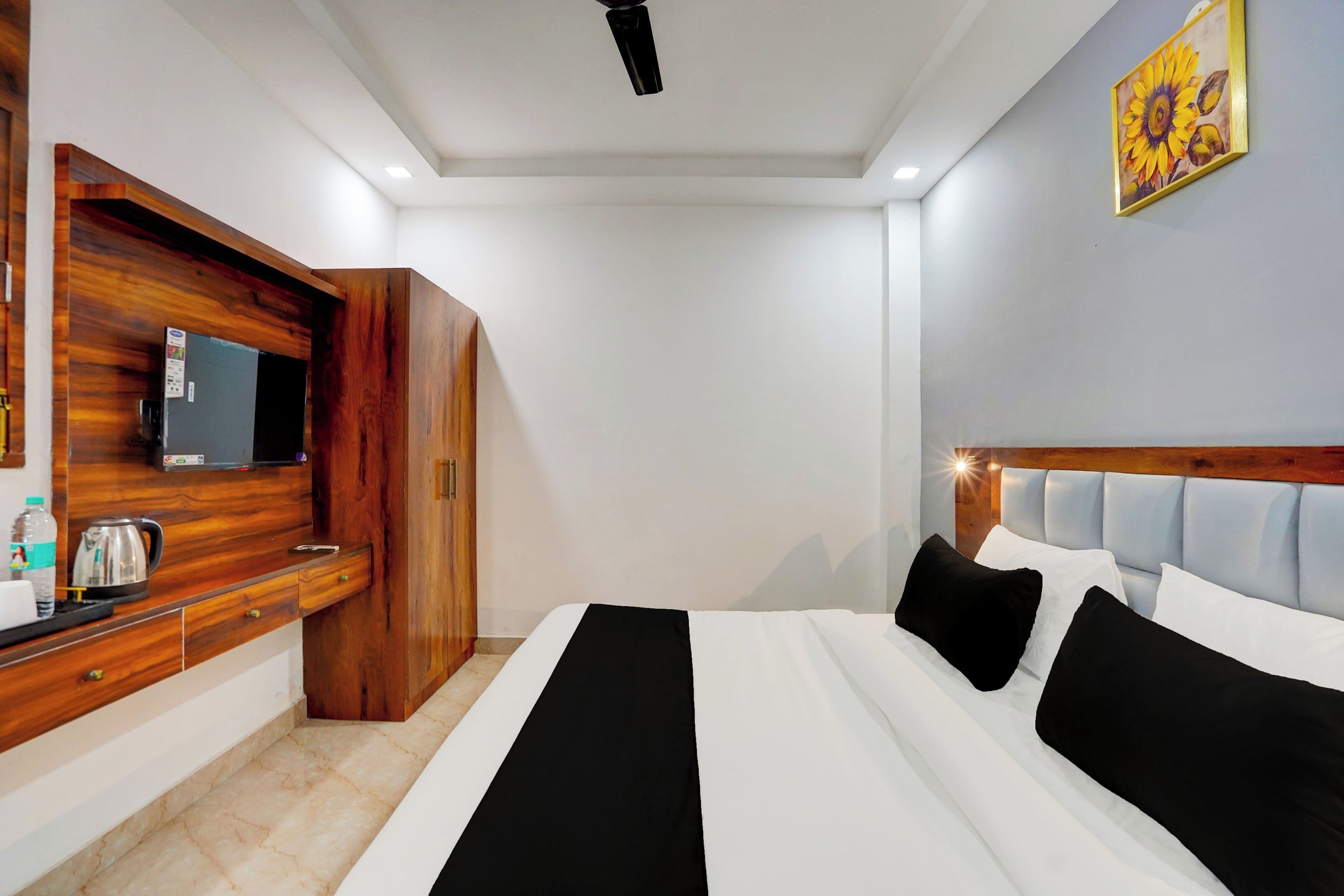 Ein Hotelzimmer mit einem Bett, einem Fernseher, einem Holzschrank und einem Bild an der Wand.