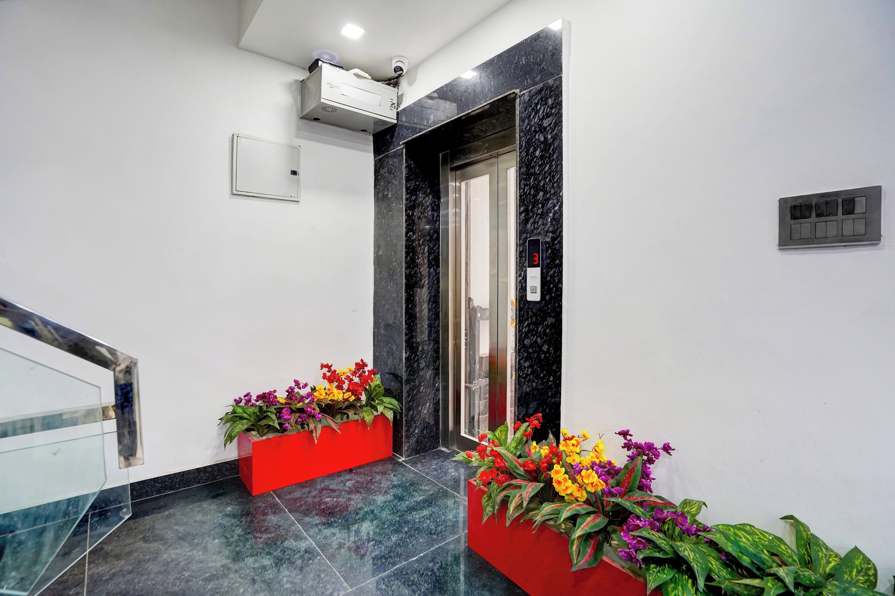 Ein moderner Aufzug mit digitaler Anzeige, einem roten Blumentopf mit Blumen und einem Marmorboden.