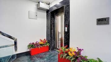 Ein moderner Aufzug mit digitaler Anzeige, einem roten Blumentopf mit Blumen und einem Marmorboden.