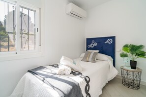 A bedroom with a bed, a window, an air conditioning unit, a headboard, a bedside table with a plant, and a decorative wall piece. - Cubo's Casa El Americano / private pool / air conditioning / BBQ / free Wi-Fi (Guaro)