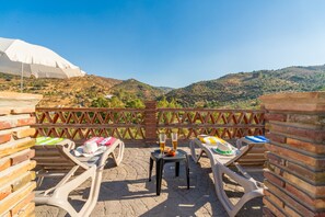 A terrace with two sun loungers, a table with drinks, and a view of a hilly landscape. - Cubo's Casa El Americano / private pool / air conditioning / BBQ / free Wi-Fi (Guaro)