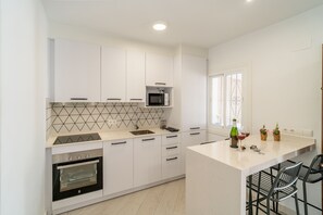 A modern kitchen with white cabinets, a microwave, an oven, and a tiled backsplash. - Cubo's Casa El Americano / private pool / air conditioning / BBQ / free Wi-Fi (Guaro)