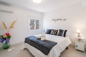 A hotel room with a bed, a nightstand, a lamp, a window with a view, and a wall decoration. - Cubo's Casa El Americano / private pool / air conditioning / BBQ / free Wi-Fi (Guaro)