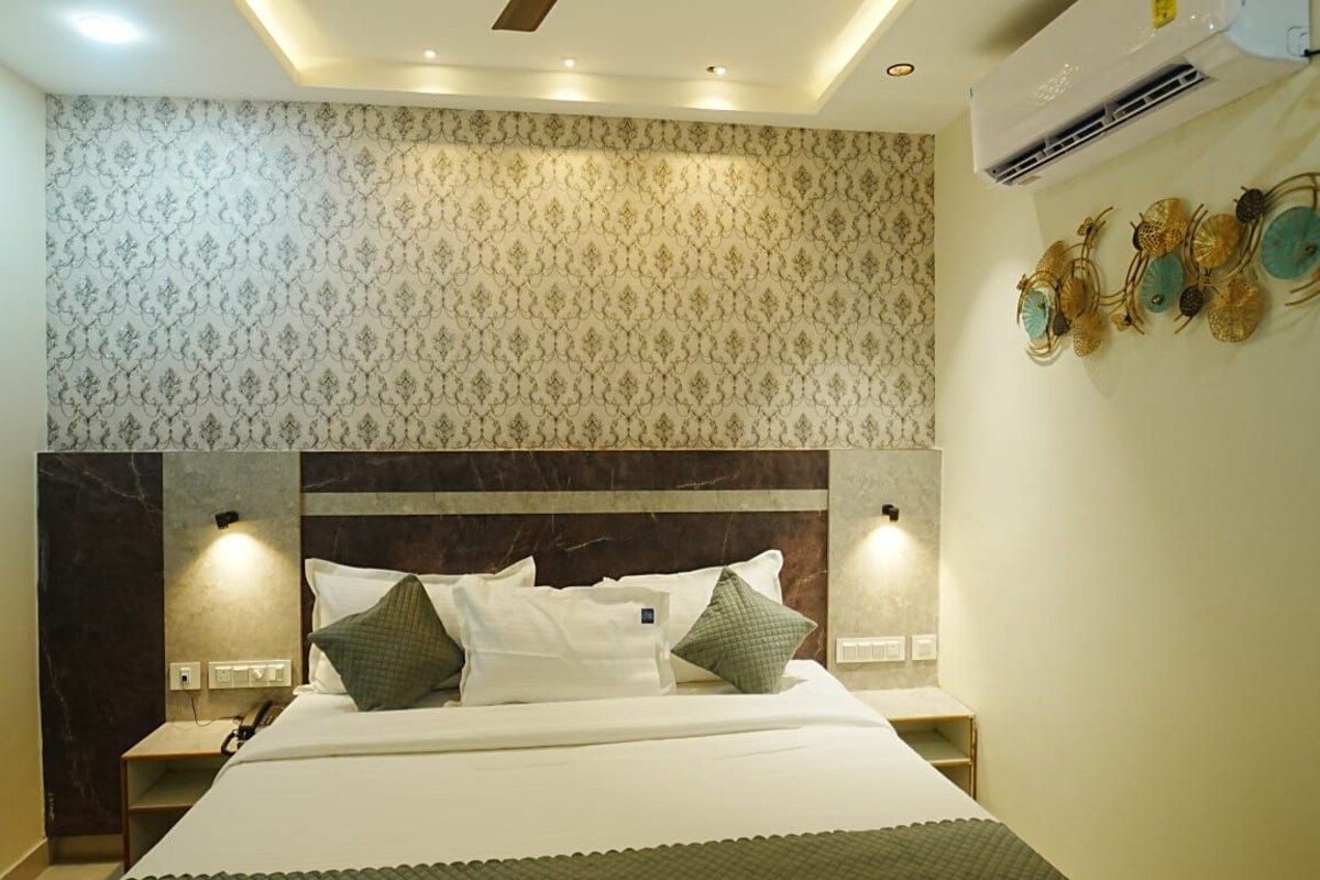 A hotel room with a bed, nightstands, an air conditioning unit, and decorative wall art.