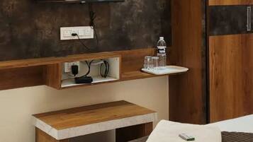 A modern bedroom with a bed, a TV mounted on a textured wall, a wooden bedside table, and a wardrobe.
