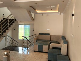 Una sala moderna con una escalera, un conjunto de sofás y una esfera decorativa.