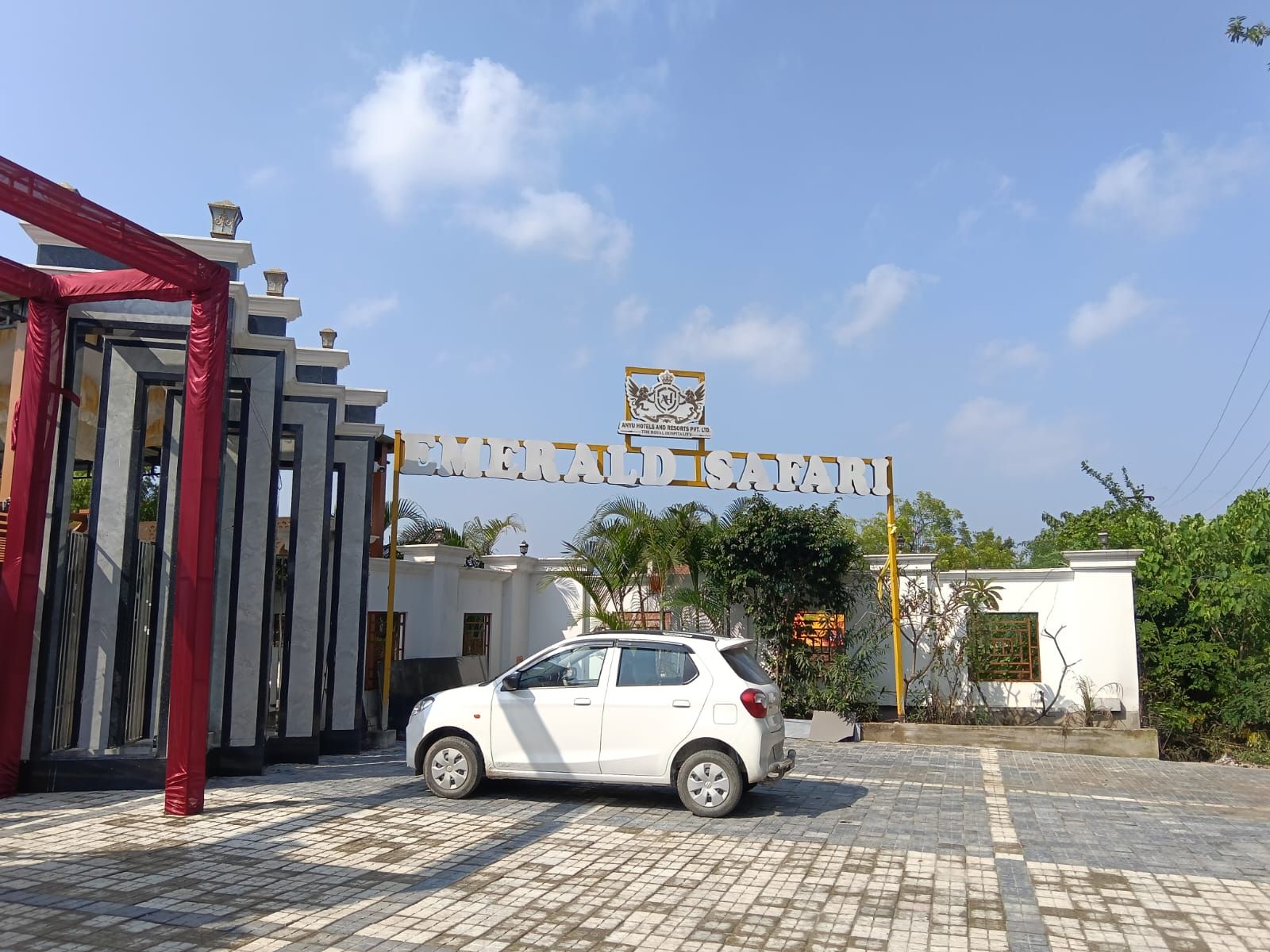 Une voiture blanche est garée devant un bâtiment sur lequel on peut lire l’inscription « EMERALD SAFARI ».