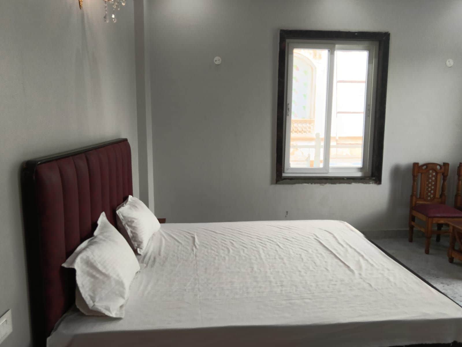 Quarto com cama, janela e cadeira.
