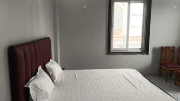 Quarto com cama, janela e cadeira.