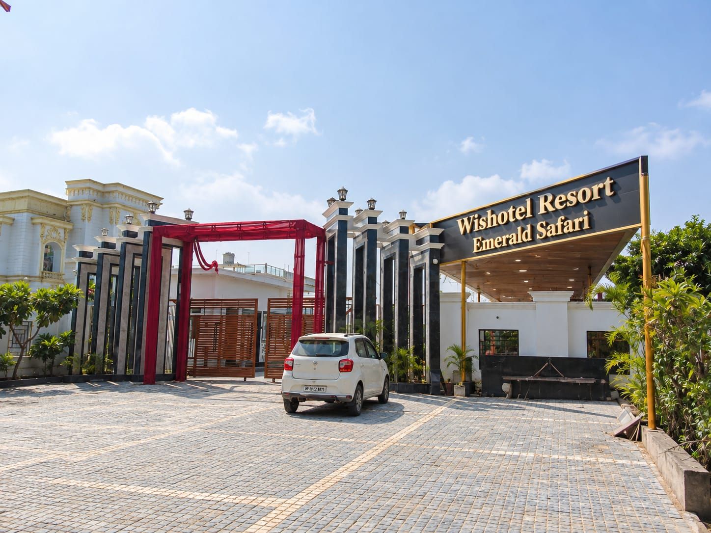 A car parked in front of the entrance to Wishotel Resort Emerald Safari.