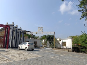 A gated entrance with a sign reading 'EMERALD SAFARI' and a white car parked in front.