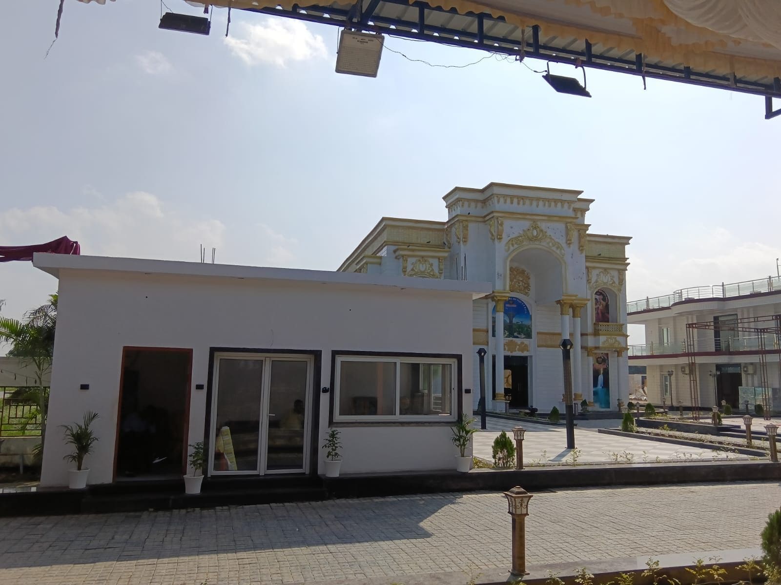Un edificio con fachada blanca, ventanas grandes y entrada protegida por una reja.