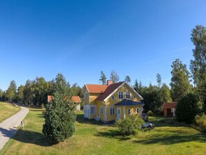 A two-story yellow house with a red roof, surrounded by a well-maintained lawn and trees. - Holiday Home With 4 Bedrooms (Ambjörnarp)